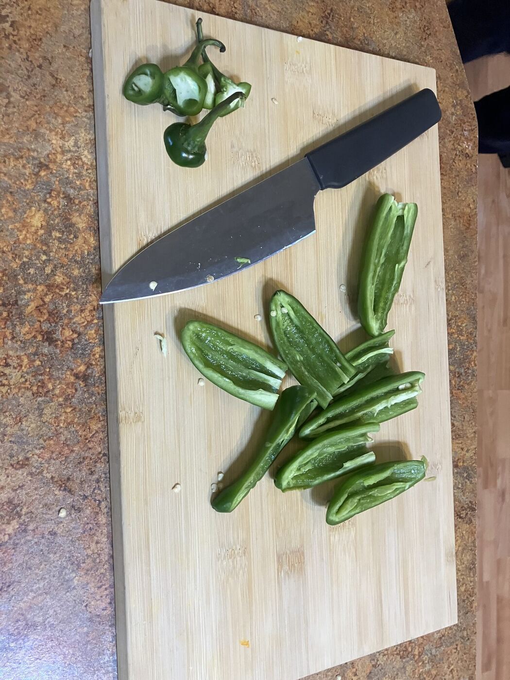 Halved green peppers and a knife on a cutting board