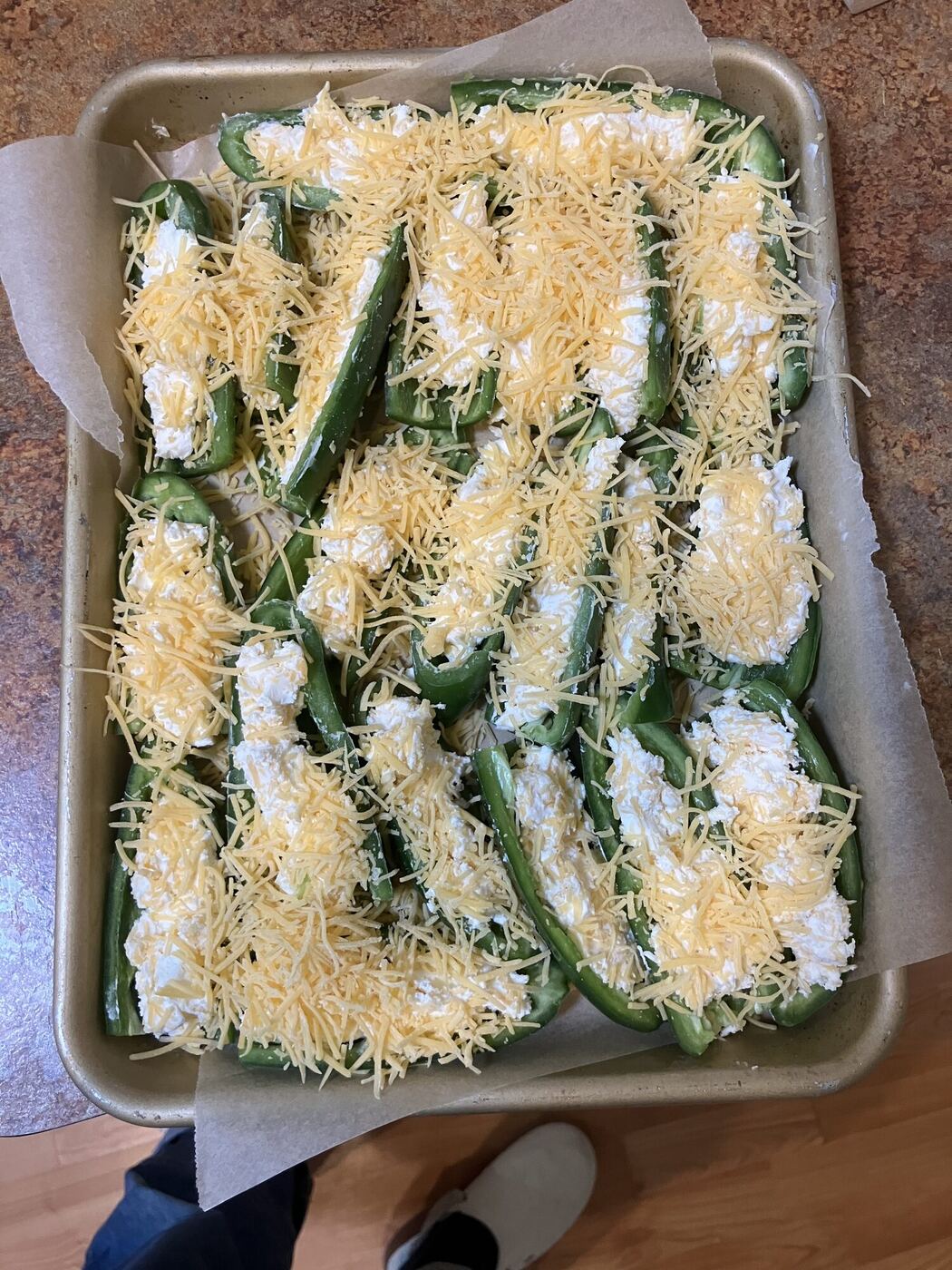 A tray of stuffed peppers under grated cheese